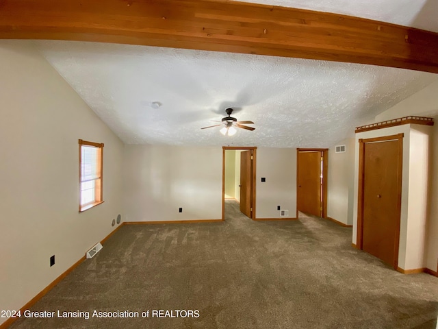 carpeted spare room with a textured ceiling, vaulted ceiling, and ceiling fan