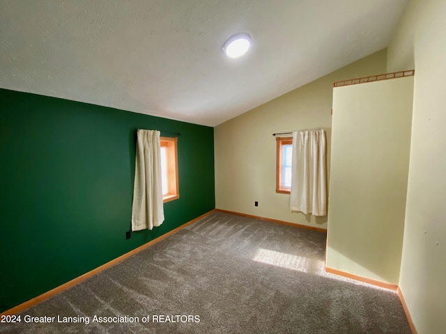 carpeted spare room featuring vaulted ceiling