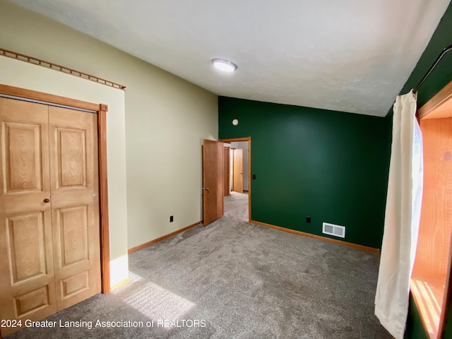 unfurnished bedroom featuring a closet, carpet floors, and lofted ceiling