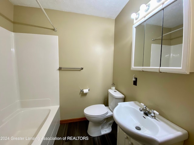 full bathroom featuring hardwood / wood-style floors, sink, shower / washtub combination, toilet, and a textured ceiling