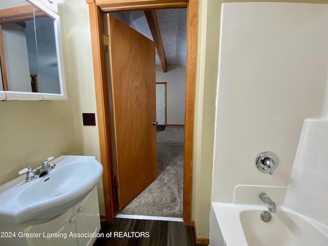 bathroom featuring beamed ceiling, hardwood / wood-style flooring, shower / bathtub combination, and sink