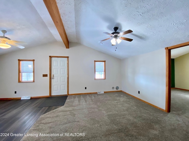 interior space with vaulted ceiling with beams, dark wood-type flooring, a healthy amount of sunlight, and a textured ceiling