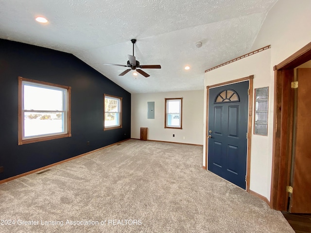 interior space featuring a textured ceiling, ceiling fan, light carpet, and lofted ceiling