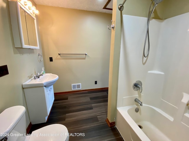 full bathroom featuring vanity, a textured ceiling,  shower combination, wood-type flooring, and toilet