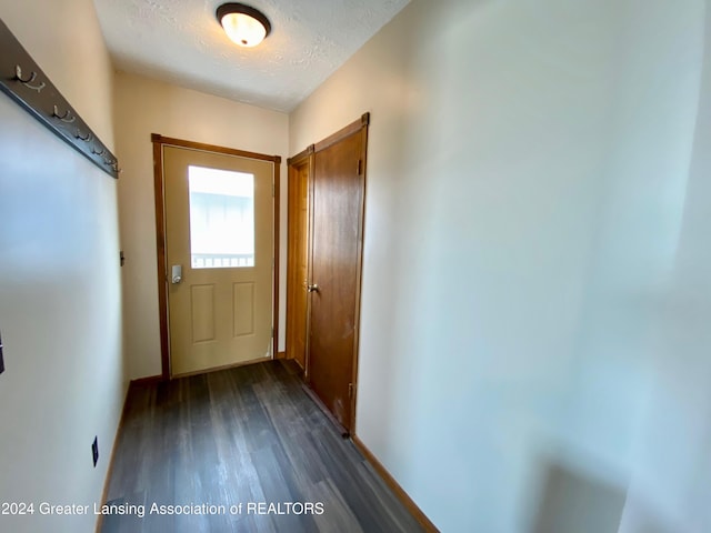 doorway to outside with dark wood-type flooring and a textured ceiling