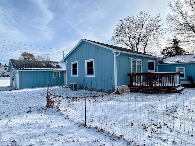 snow covered back of property with central AC and a wooden deck