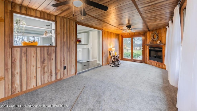 unfurnished living room with carpet flooring, wooden walls, and wooden ceiling