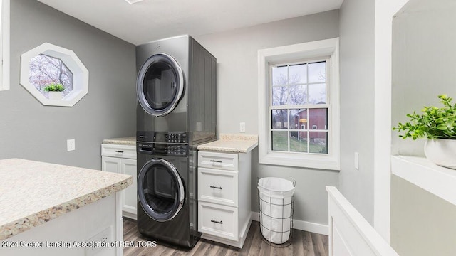 laundry room with cabinets, dark wood-type flooring, and stacked washer / drying machine