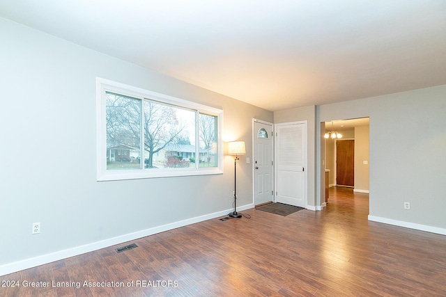 empty room featuring dark hardwood / wood-style floors and an inviting chandelier