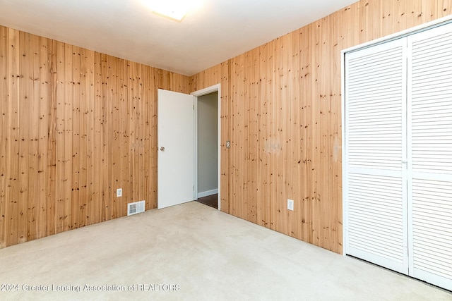 carpeted empty room featuring wood walls