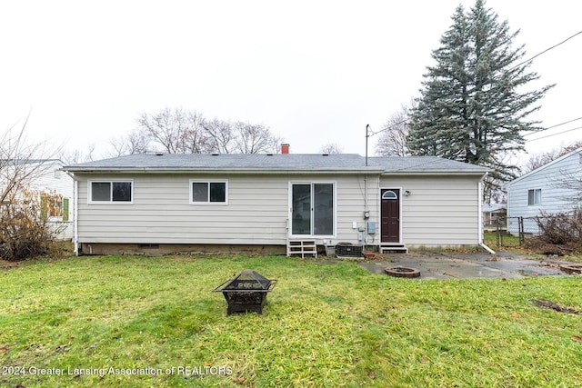 back of house with an outdoor fire pit and a lawn