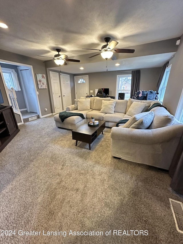 carpeted living room featuring ceiling fan and a textured ceiling