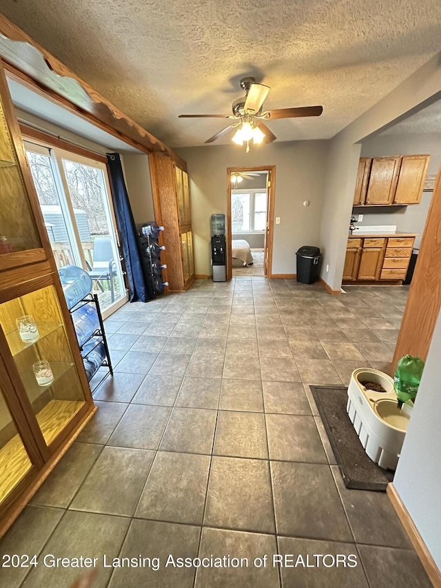 interior space featuring tile patterned flooring, ceiling fan, a textured ceiling, and a wealth of natural light