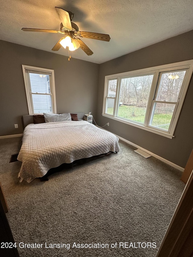 bedroom featuring ceiling fan, carpet, and a textured ceiling