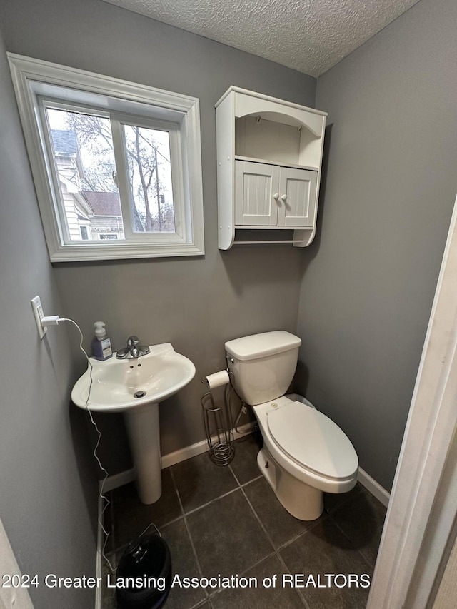 bathroom featuring tile patterned floors, toilet, and a textured ceiling