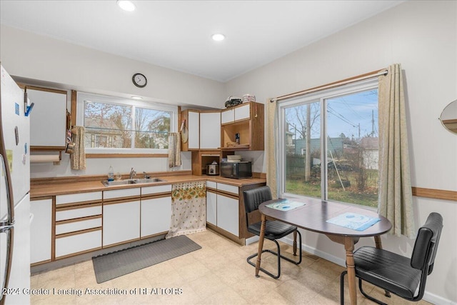 kitchen featuring white cabinets, white fridge, and sink