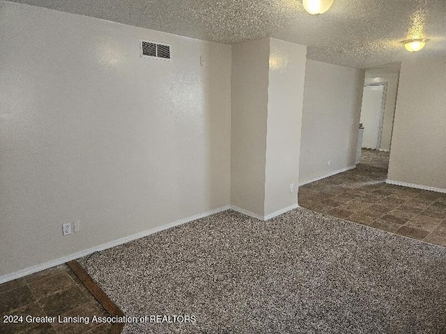 carpeted spare room featuring a textured ceiling