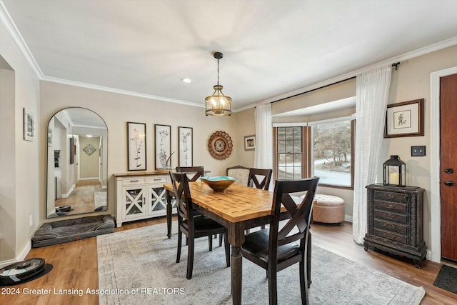 dining space featuring wood-type flooring and crown molding