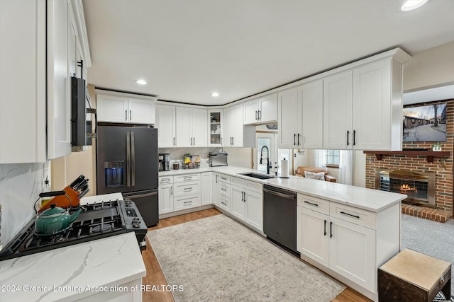 kitchen with white cabinets, stainless steel appliances, light stone counters, and sink