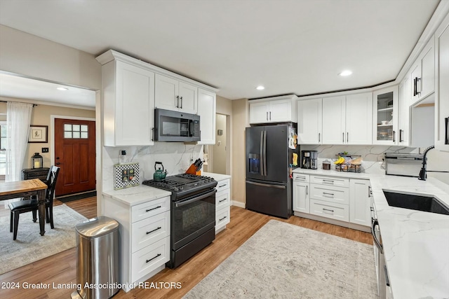 kitchen with white cabinets, sink, light stone countertops, tasteful backsplash, and stainless steel appliances