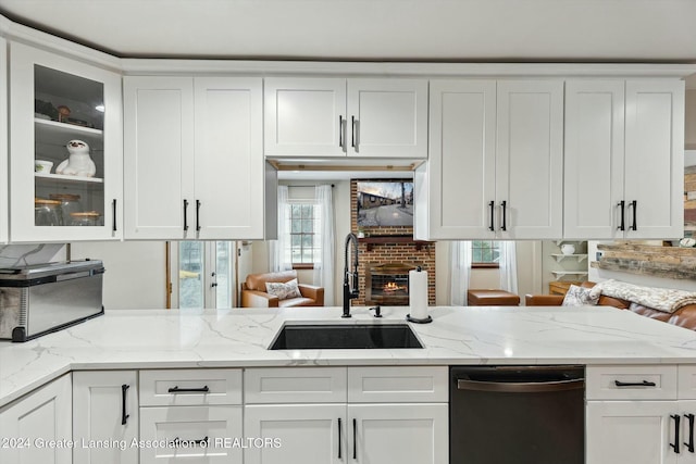 kitchen featuring white cabinets, dishwasher, light stone countertops, and sink