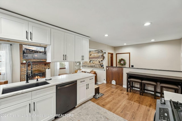 kitchen with white cabinetry, dishwasher, sink, light stone counters, and light wood-type flooring