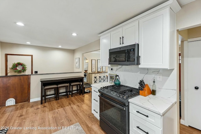 kitchen with gas stove, white cabinetry, tasteful backsplash, and light stone counters