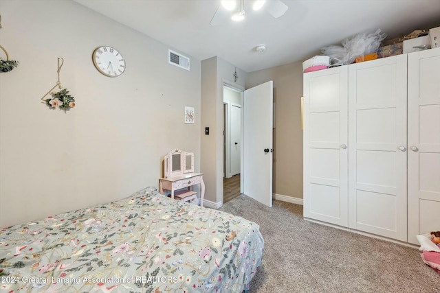 bedroom with ceiling fan, light carpet, and a closet