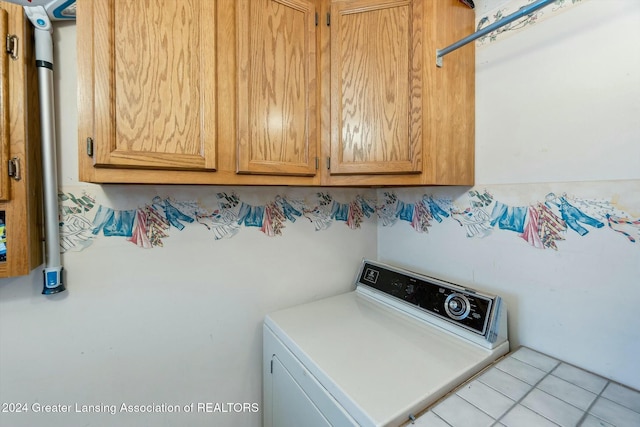 washroom with light tile patterned flooring, cabinets, and washer / dryer