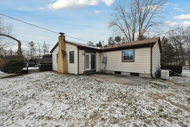 snow covered house featuring central AC and a patio area