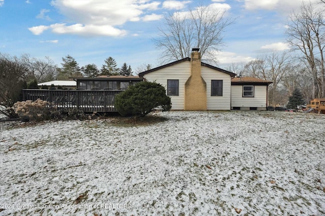 snow covered property featuring a wooden deck and a sunroom