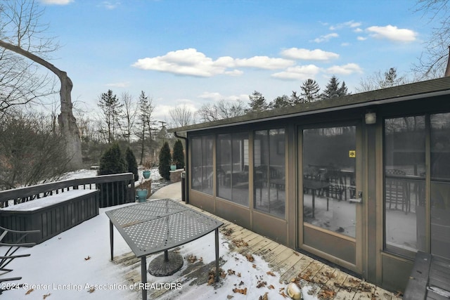 snow covered deck featuring a sunroom