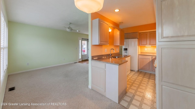 kitchen featuring ceiling fan, white fridge with ice dispenser, sink, and light carpet