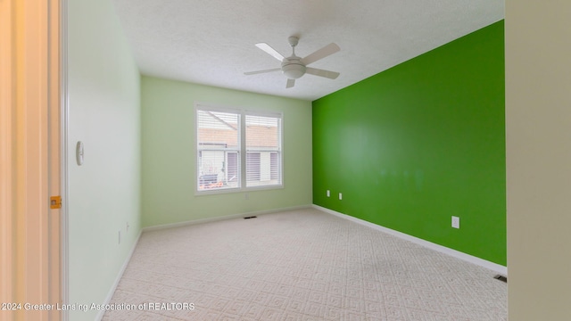 unfurnished room featuring ceiling fan, light carpet, and a textured ceiling