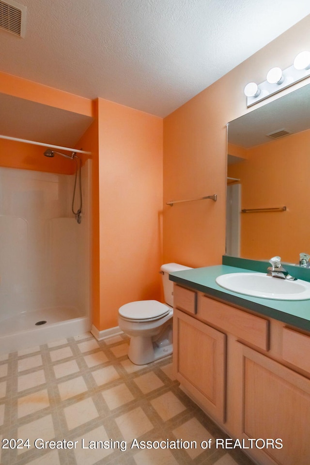 bathroom featuring vanity, toilet, a shower, and a textured ceiling