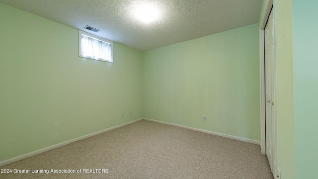 carpeted empty room featuring a textured ceiling