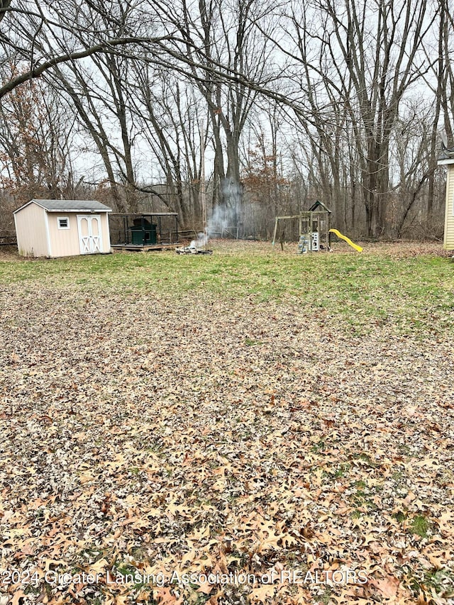 view of yard with a storage shed and a playground