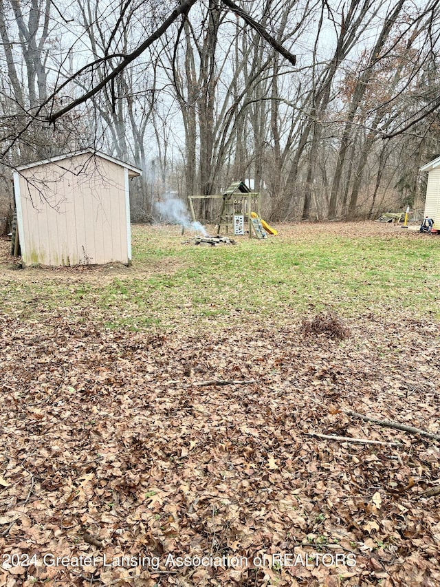 view of yard with a storage unit and a playground