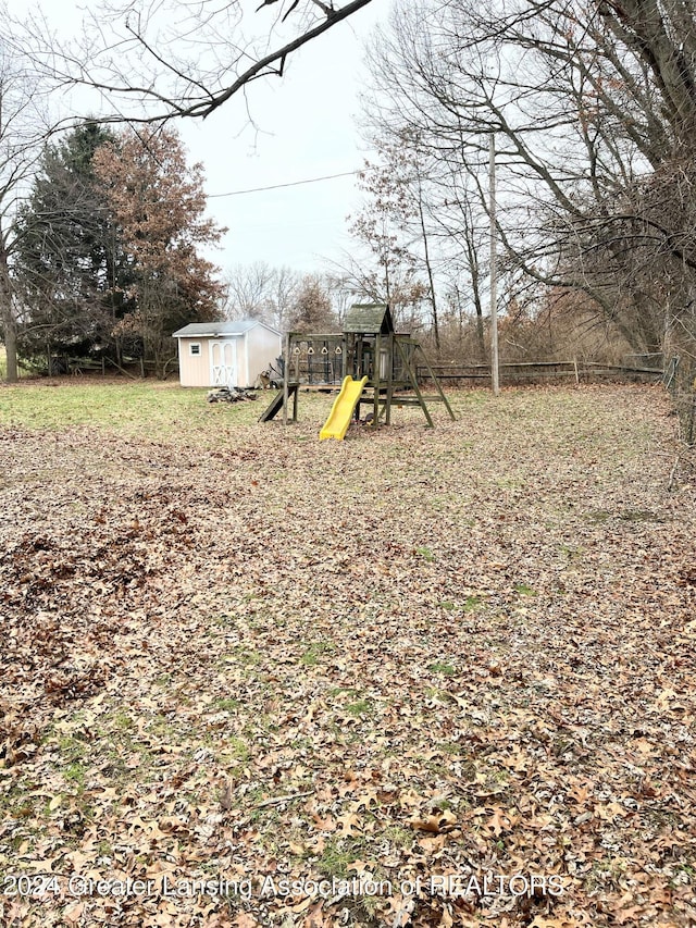 view of yard featuring a storage unit and a playground