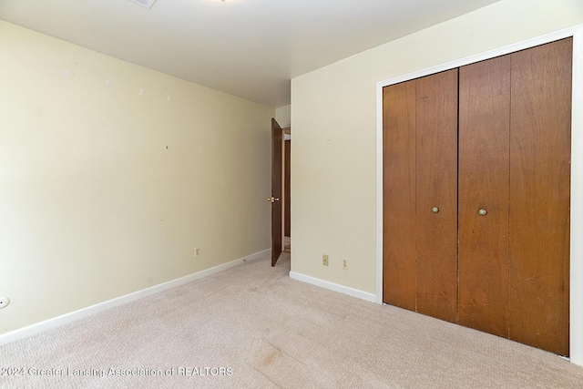 unfurnished bedroom featuring light colored carpet and a closet