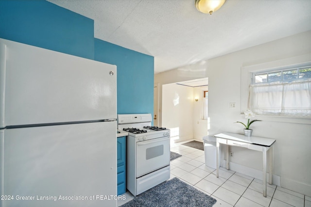 kitchen featuring blue cabinetry, light tile patterned floors, white appliances, and a textured ceiling