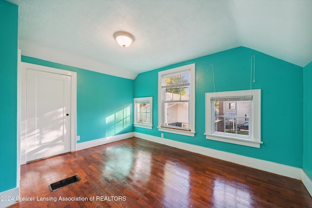 additional living space featuring a textured ceiling, hardwood / wood-style flooring, and lofted ceiling