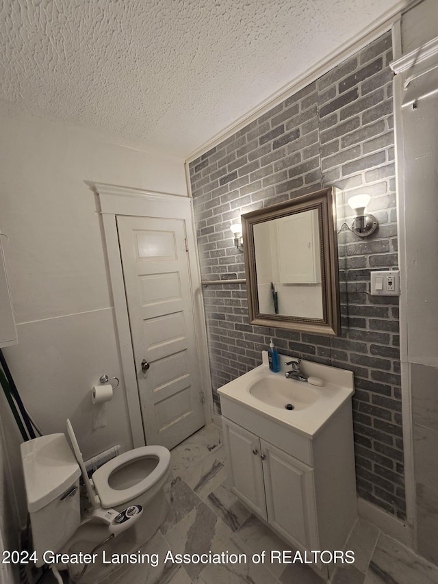 bathroom with vanity, a textured ceiling, toilet, and brick wall