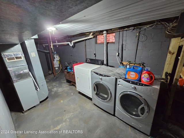 clothes washing area featuring heating unit, washer and dryer, and gas water heater