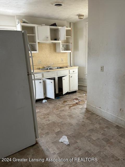 kitchen featuring decorative backsplash, sink, white cabinets, and white refrigerator