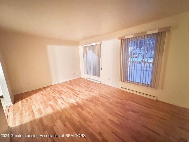 unfurnished room with hardwood / wood-style flooring and a baseboard heating unit