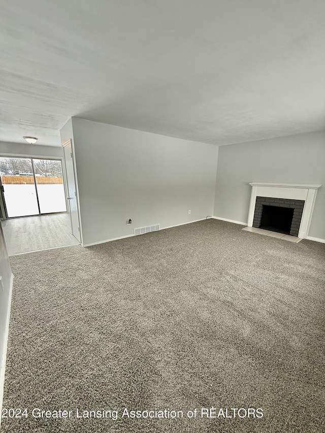 unfurnished living room with carpet flooring and a fireplace