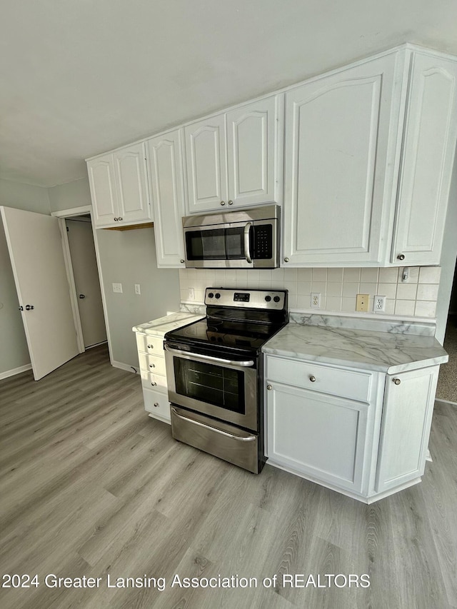 kitchen featuring appliances with stainless steel finishes, light hardwood / wood-style flooring, white cabinetry, and tasteful backsplash