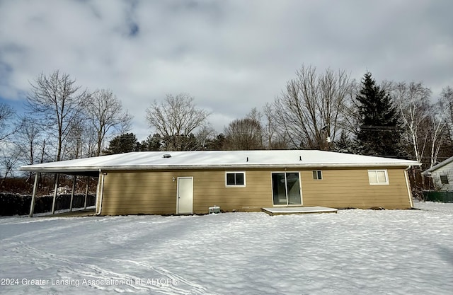 snow covered house featuring a carport