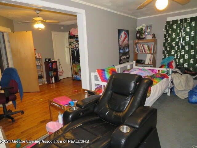 bedroom with hardwood / wood-style floors, ceiling fan, and ornamental molding